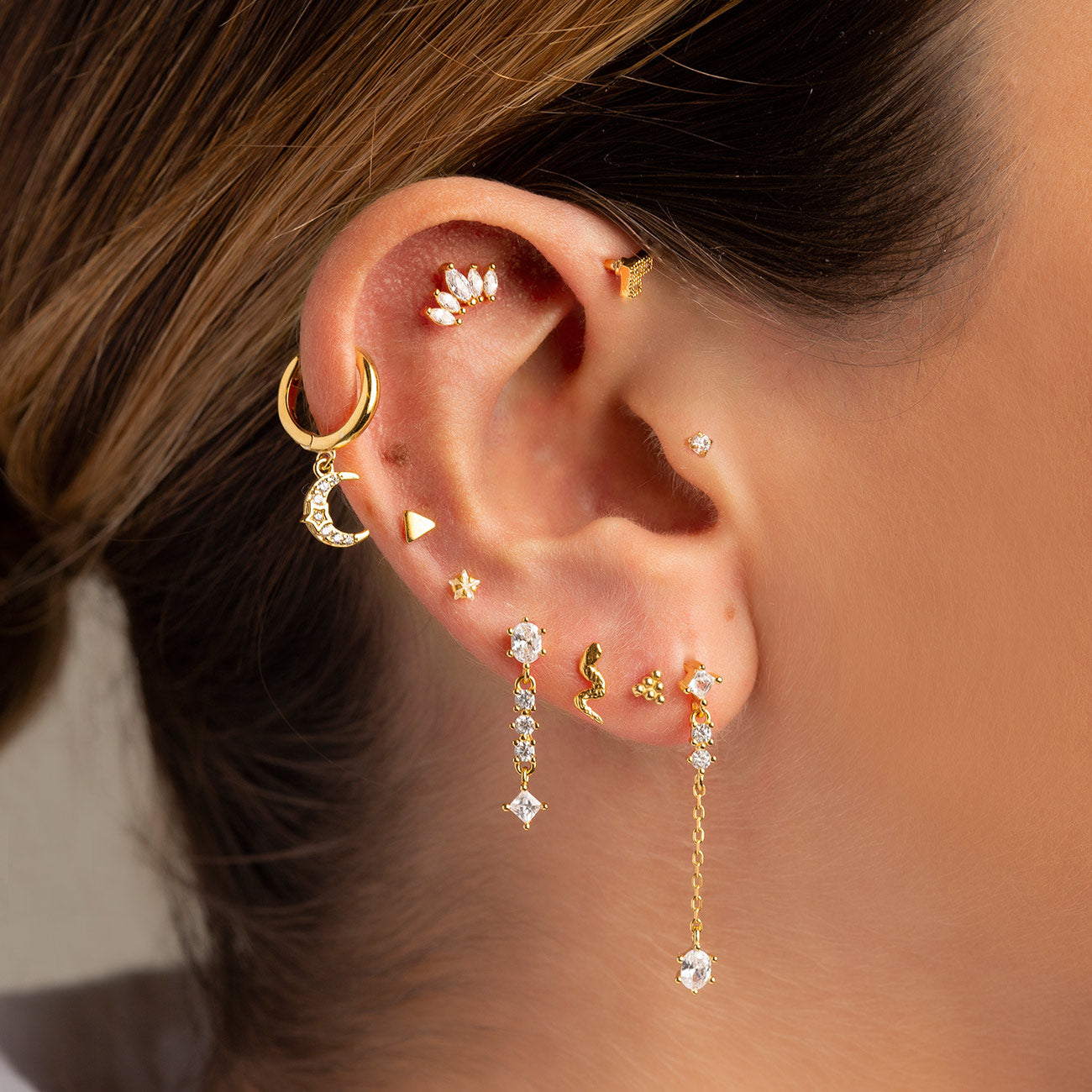 Oreja de mujer con pendiente Triangle Mini Gold y otros pendientes de oro de la colección de Adamina